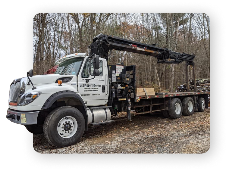 A white truck with a crane, branded with "CES Property Service," parked on a construction site.
